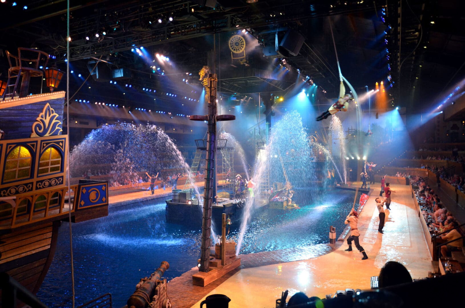A lively water-themed stage show with performers and water sprays in an arena.