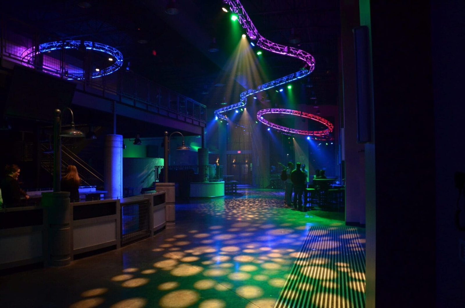 Empty nightclub with colorful lights and patterns on the dance floor.