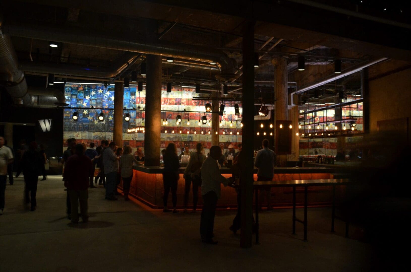 Dimly lit bar with patrons enjoying drinks and conversations.