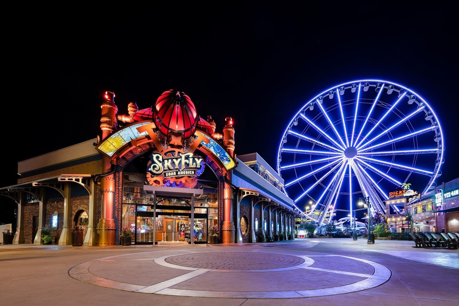 Night view of an amusement park entrance with a Ferris wheel.