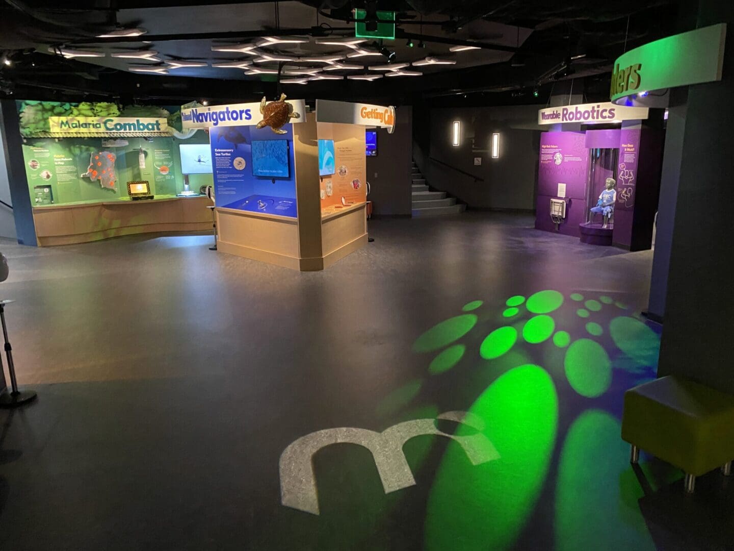 Indoor exhibition space with colorful illuminated displays and informational panels.