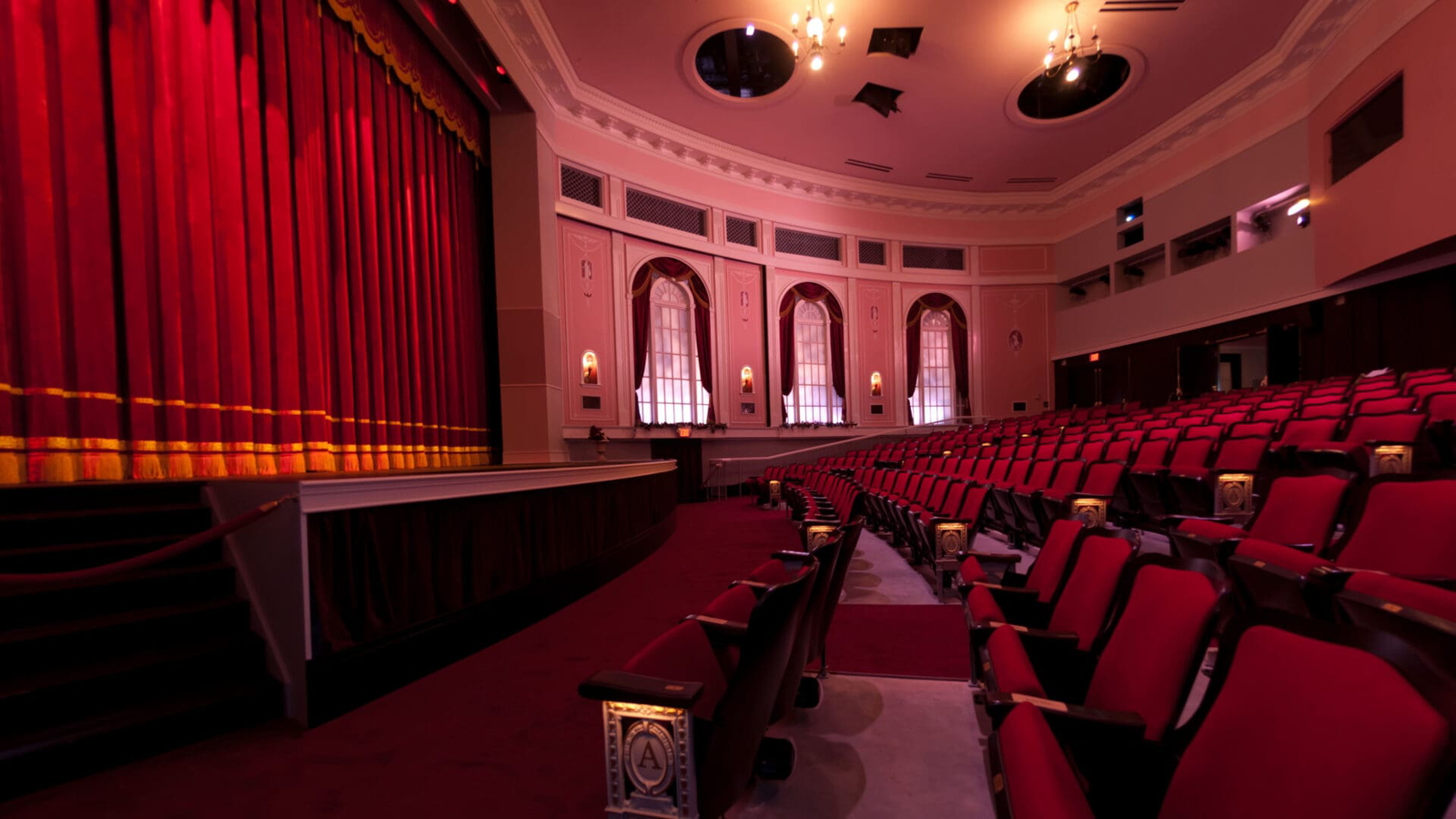 Empty theater with red seats and closed curtains.