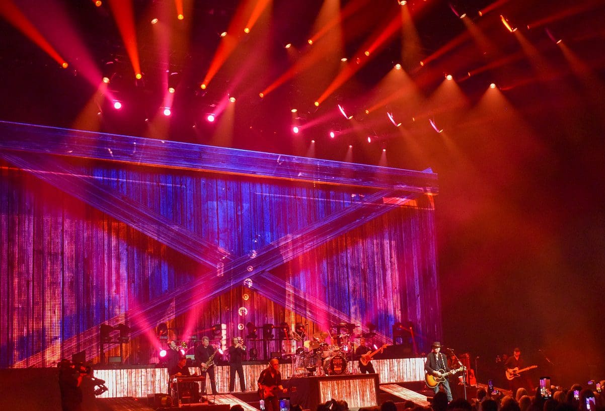 Live concert with vibrant lighting and a band performing on stage.