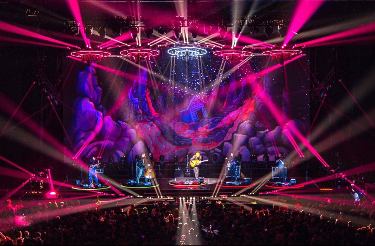 A vibrant concert with dynamic pink and purple lighting effects.