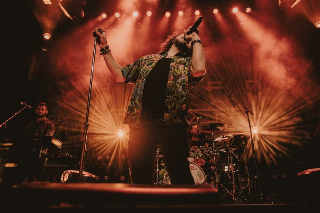 Singer passionately performing on stage under dramatic lighting.