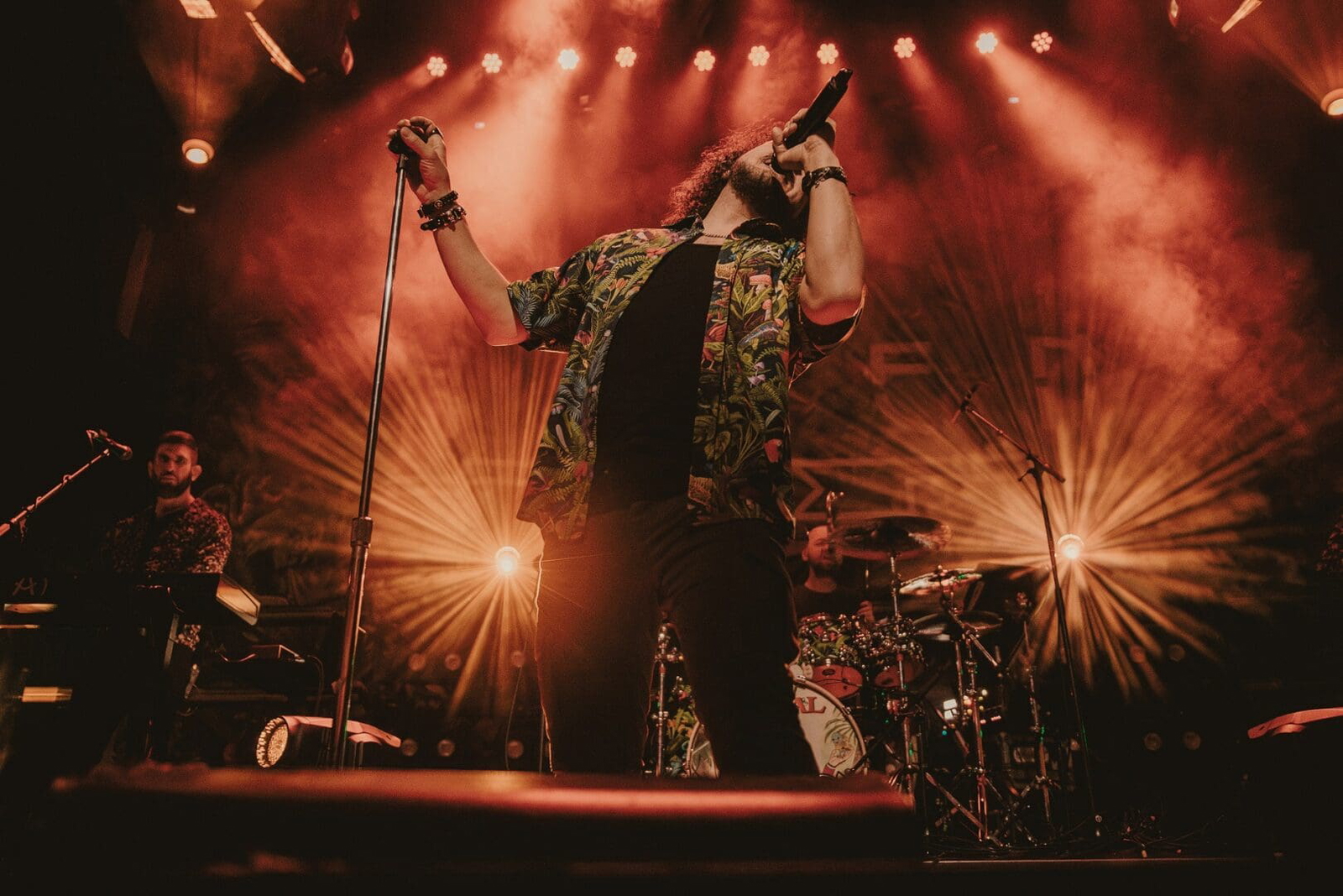 Singer passionately performing on stage under dramatic lighting.