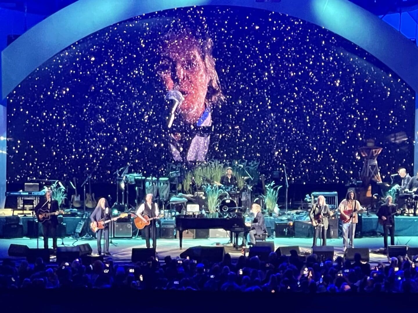Band performing on stage with vibrant blue lighting and starry background.