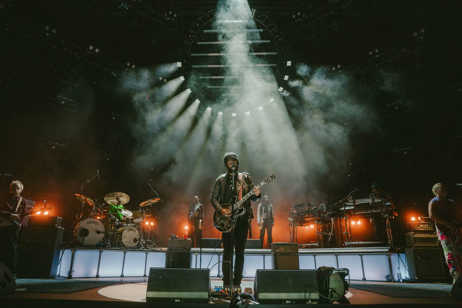 Musician playing guitar on a dimly lit stage with dramatic smoke effects.