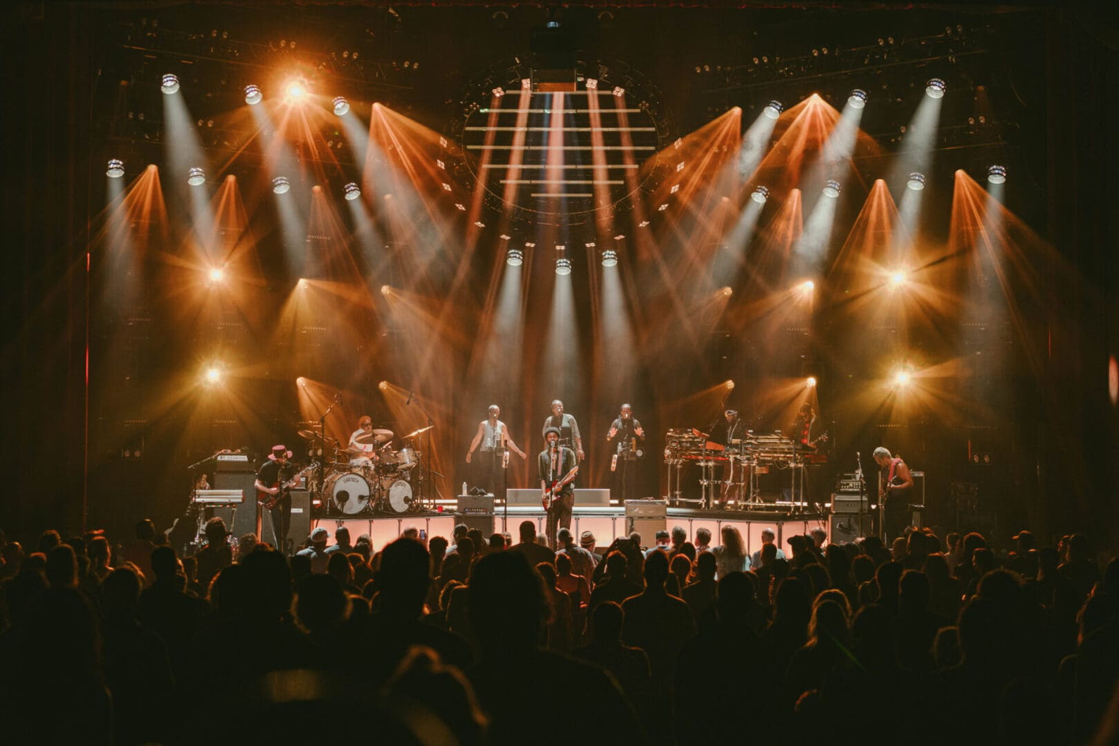 A band performing live on a brightly lit stage with an enthusiastic audience.