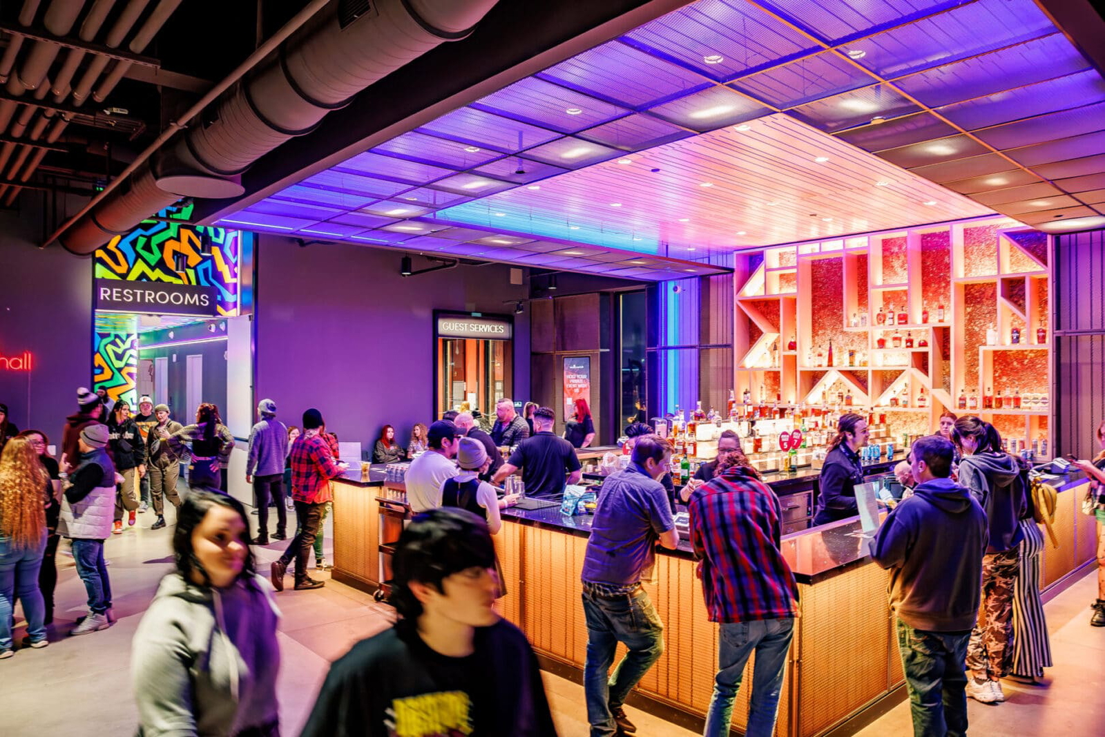 People socializing in a vibrant bar with colorful lighting.