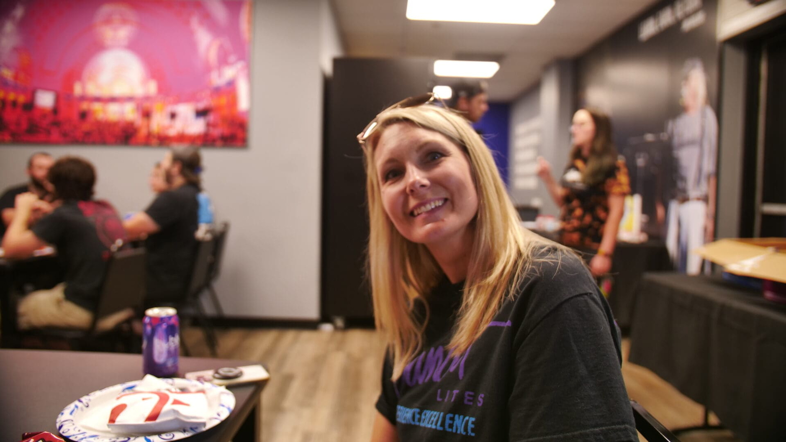 Smiling woman with sunglasses on her head in a casual indoor setting.
