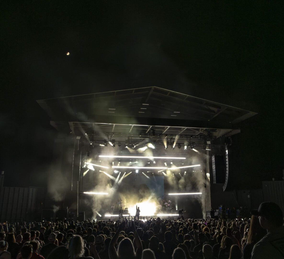 Crowd enjoying a night concert with bright stage lights.