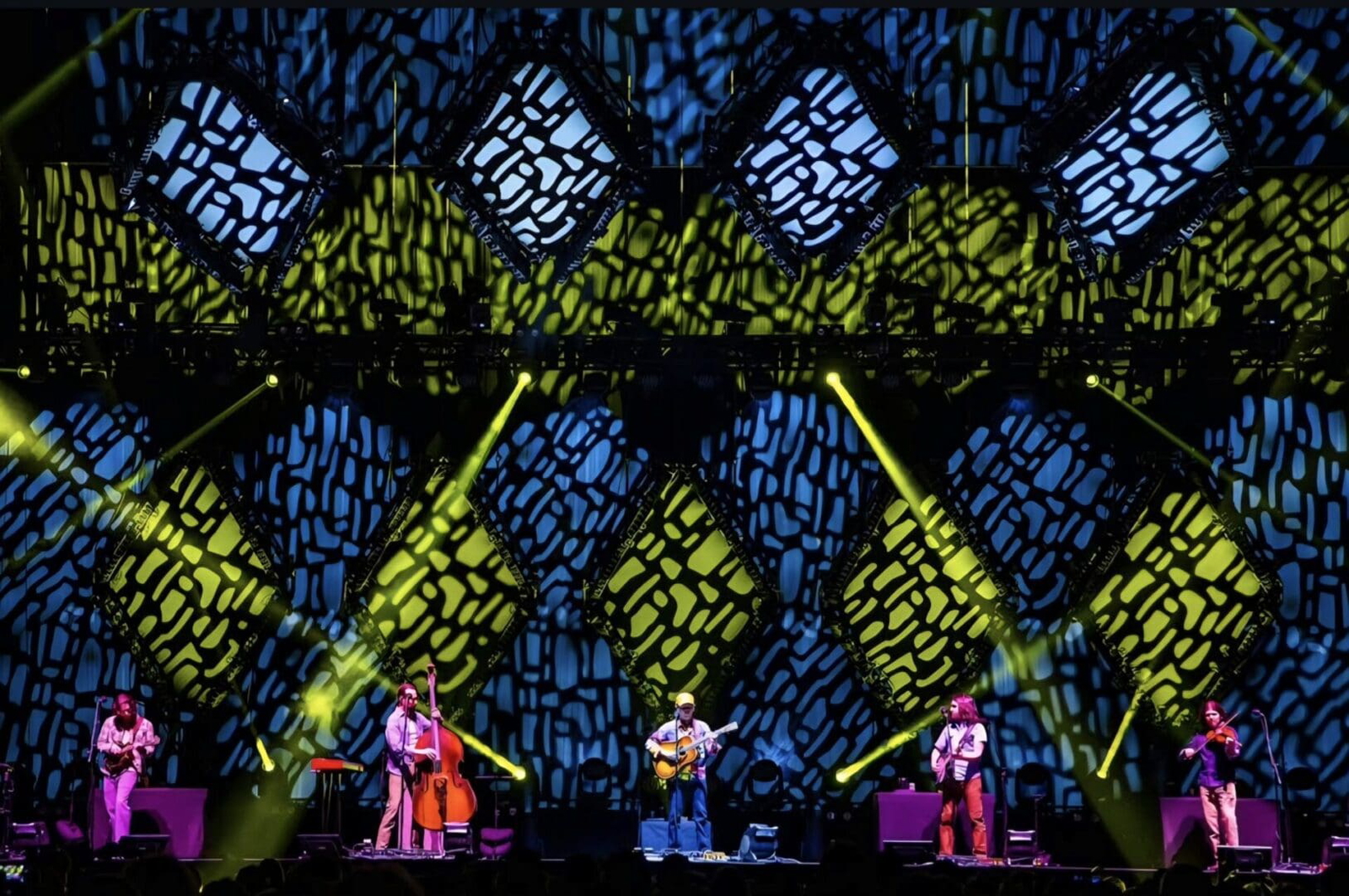 Band performing live with vibrant, geometric stage lights.