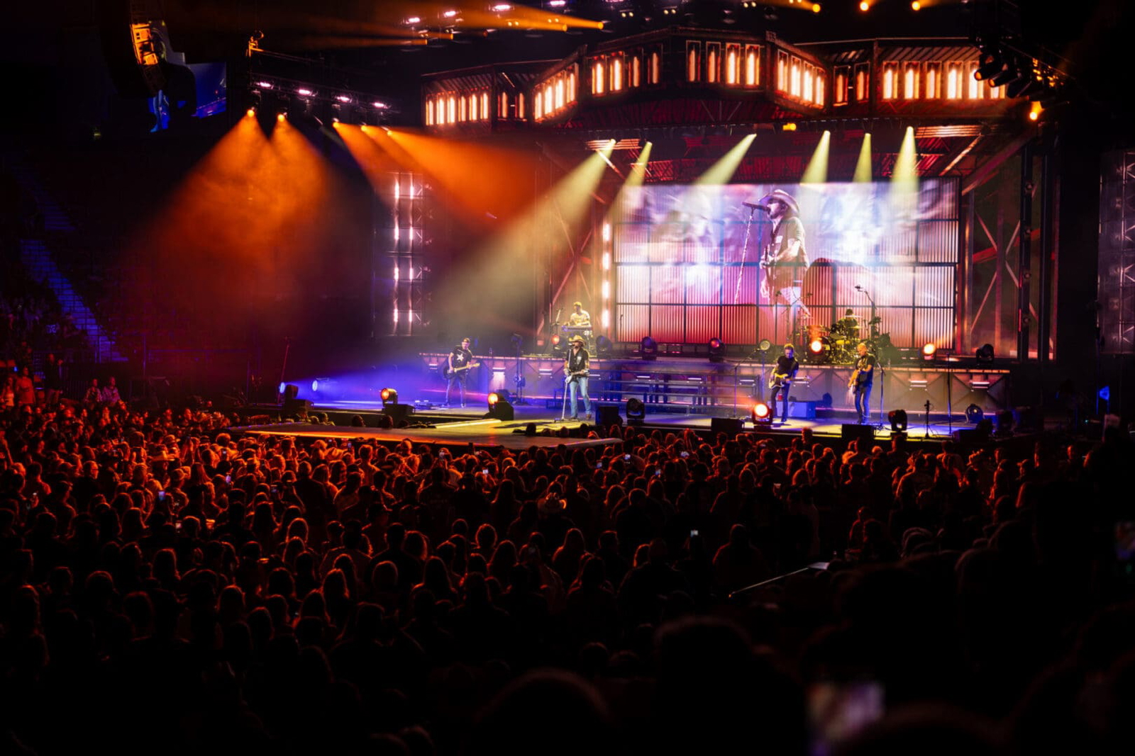 A vibrant live concert with bright stage lights and a large audience.