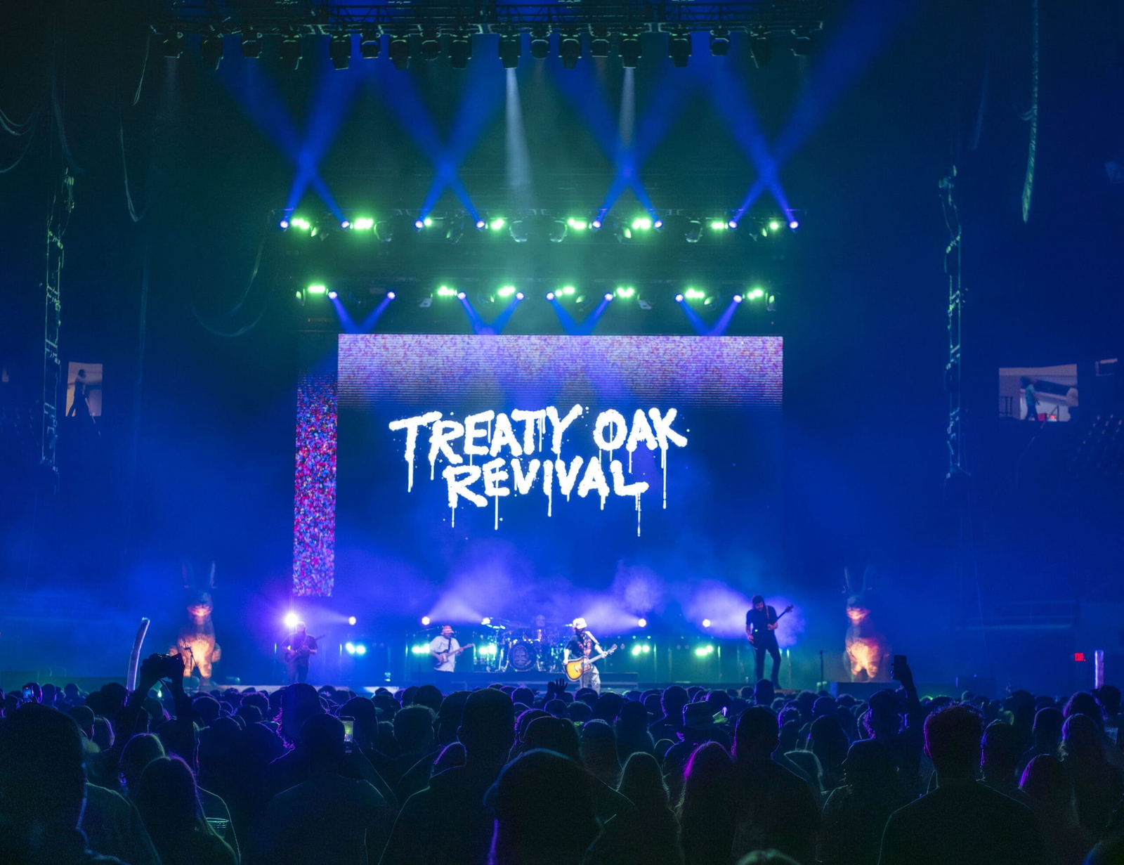 A live concert with vibrant lighting and Treaty Oak Revival on the screen.
