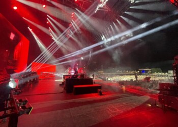 DJ performing at a vibrant nighttime concert with dramatic lighting.