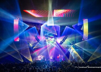 Colorful lasers and lights illuminate a crowded concert stage.