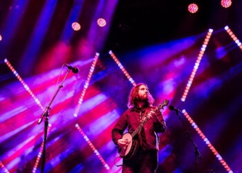 Musician performing on stage with vibrant colorful lights.
