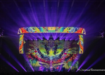 Vibrant tie-dye decorations with dynamic lighting create a psychedelic stage atmosphere.