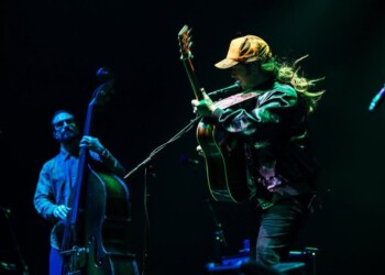 Musicians passionately playing guitar and double bass on stage under blue lighting.