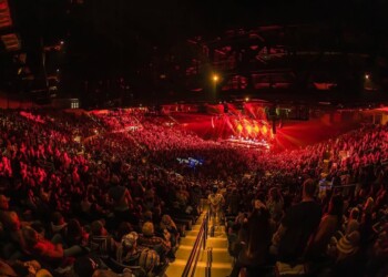 Crowded stadium with vibrant red lighting during a night event.