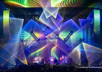 Colorful laser lights and geometric projections at a live concert stage.