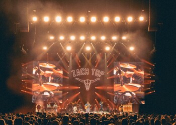 Concert stage with bright lights and crowd in front.