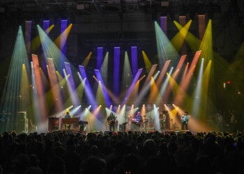 Colorful stage lights illuminate performers at a lively concert.
