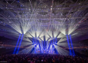 A concert with vibrant blue and white stage lights illuminating the crowd.