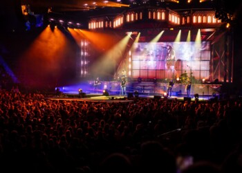 A vibrant concert stage with bright lights and a large crowd.