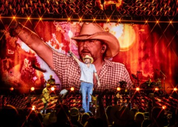 A cowboy-themed performer entertains a lively crowd with bright stage lights.