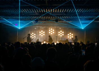 Concert scene with bright stage lights and laser effects.