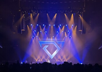 Concert stage with vibrant blue and purple lights and a geometric heart design.