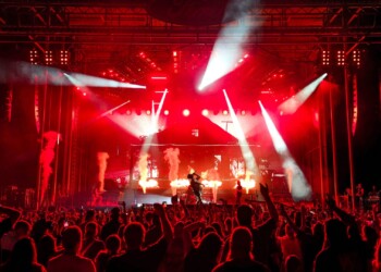 Energetic live concert with vibrant red lighting and enthusiastic crowd.