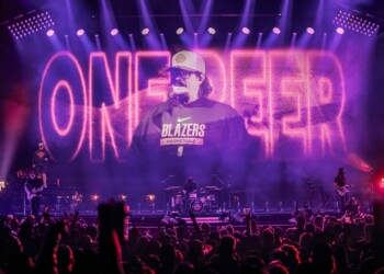 Concert stage with vibrant pink lights and a performer on screen.