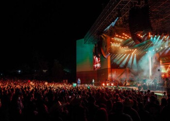 Large crowd enjoying a nighttime outdoor concert with vibrant stage lights.
