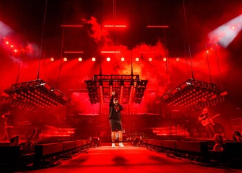 A performer on stage bathed in intense red lighting during a concert.