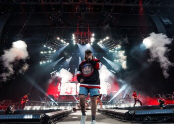 A performer on stage with dramatic lighting and smoke effects.