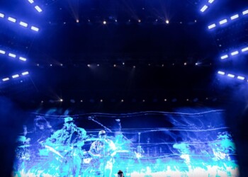 A concert stage with vibrant blue lighting and a large digital screen.