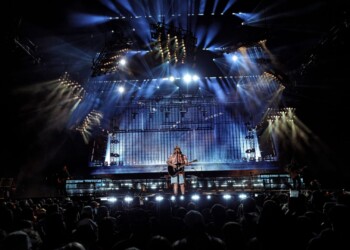 A performer on stage during a dramatic, blue-lit concert.