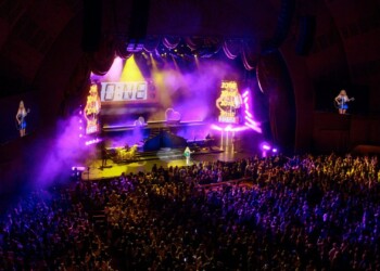 Large crowd enjoying a vibrant nighttime concert with colorful lights.