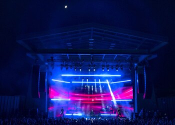 A vibrant nighttime concert with bright blue and pink stage lights.