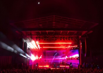 Vibrant stage lights glow red and purple in a concert setting.