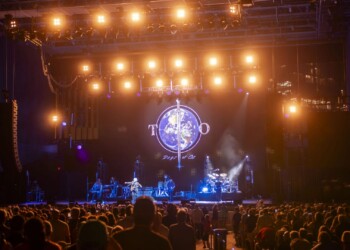 Live band performing on stage with vibrant lighting and a glowing globe backdrop.
