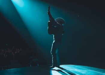 Musician performing passionately on stage under dramatic blue spotlight.