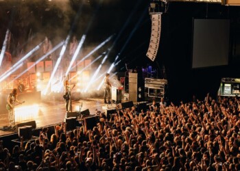 A lively concert with a large crowd and bright stage lights.
