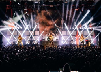 A vibrant live concert with dramatic lighting and a large crowd.
