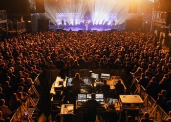 Crowded concert venue with vibrant stage lighting and live performance.