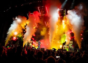 A vibrant concert scene with colorful smoke and lights illuminating the stage.
