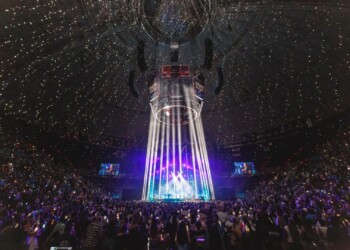 A vibrant concert with a light show and a large audience at night.